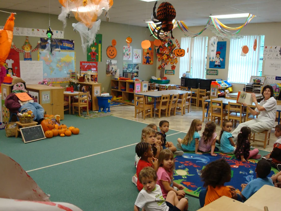 A teacher reading a story to children sitting on the carpet