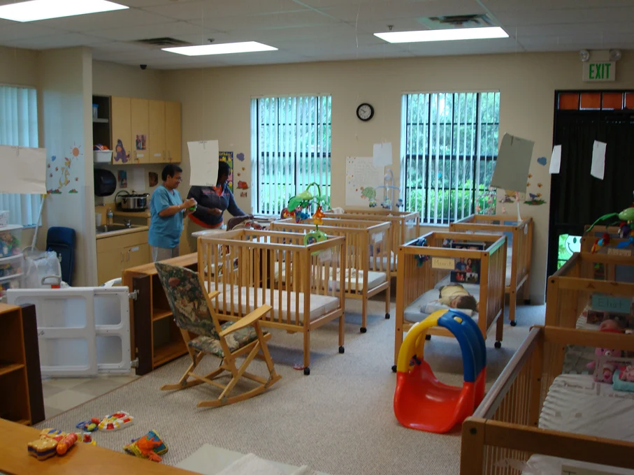 The infant room, with cribs and a caregiver